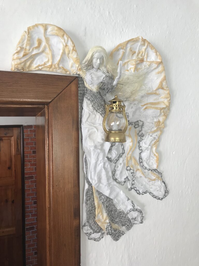 Dekorácia anjel na zárubni s rozrastenými krídlami a lampášom